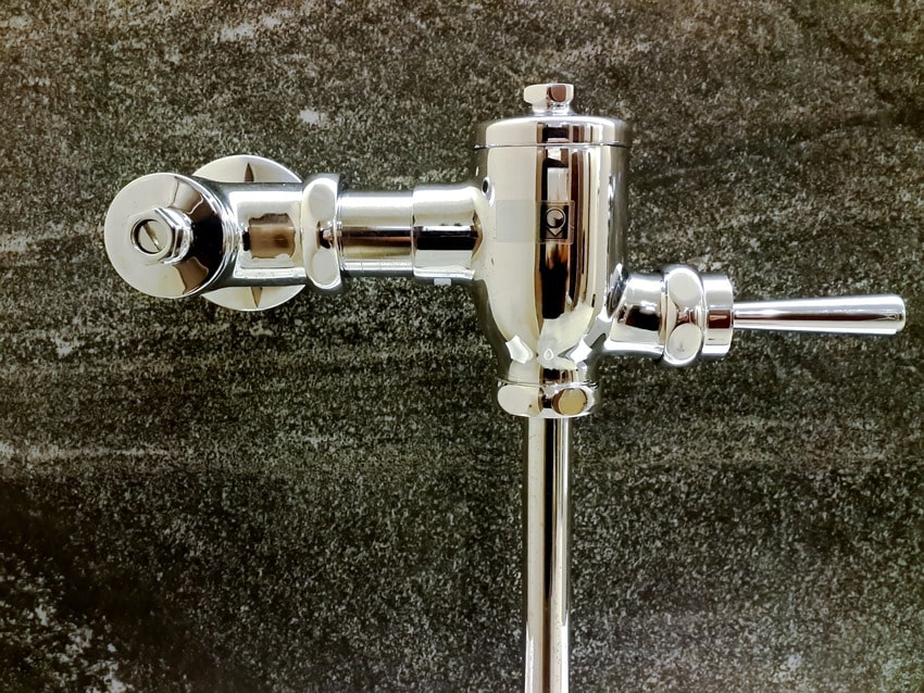 Flush valve on polished granite wall