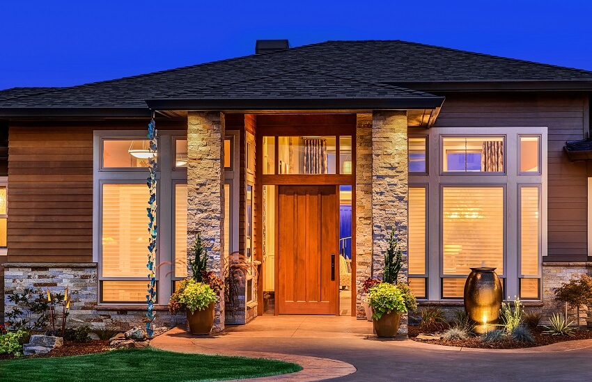Front view of a home in evening with stone columns in the porch