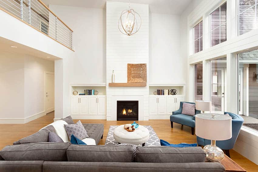 Large sectional with round ottoman, wood floors, fireplace and blue armchairs