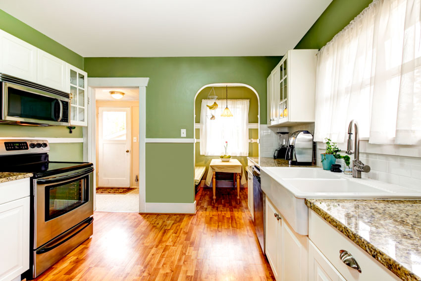 Kitchen with bright sage, countertops, sink, wood board floor, stove, oven, and window curtains