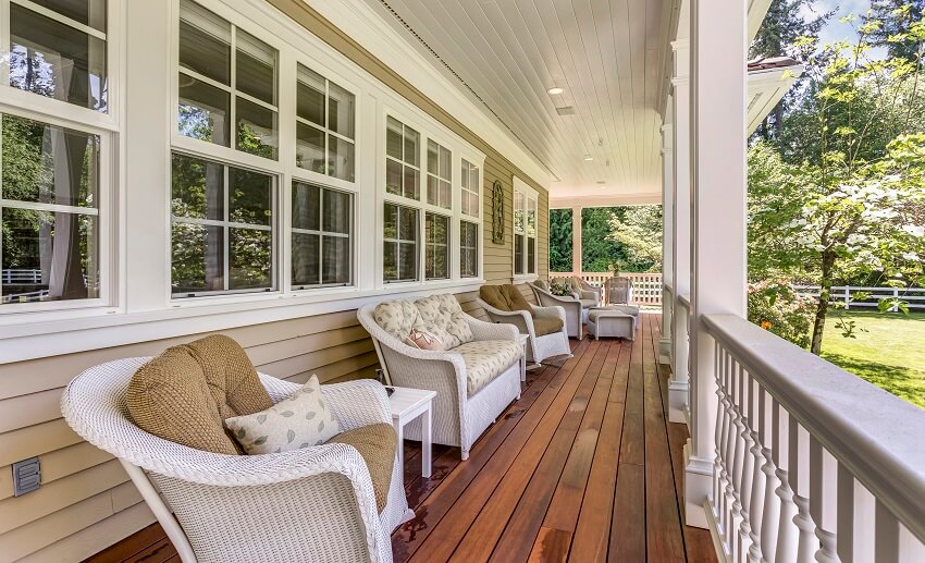 Long porch with panel wood floor, white armchairs, and sofa
