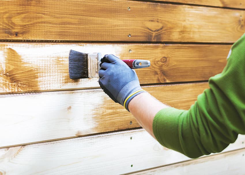 Painting varnishing siding with paint brush